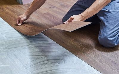 Handwerker legt Vinylboden mit Holzmotiv