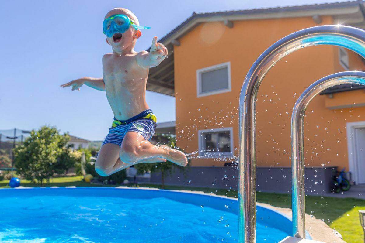 Kleiner Junge springt vergnügt in einen Gartenpool