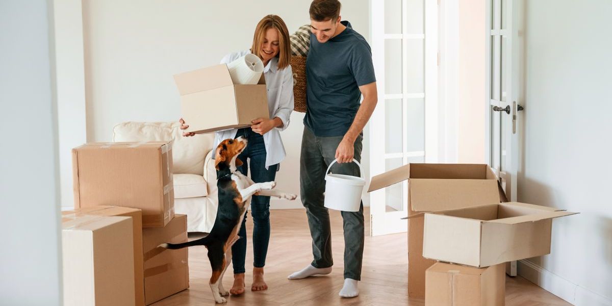 Junges Paar mit Hund und Umzugskartons in Ihrer neuen Wohnung