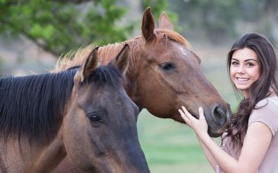 Junge Frau streichelt die Nüstern eines Pferdes, auf einem Gnadenhof
